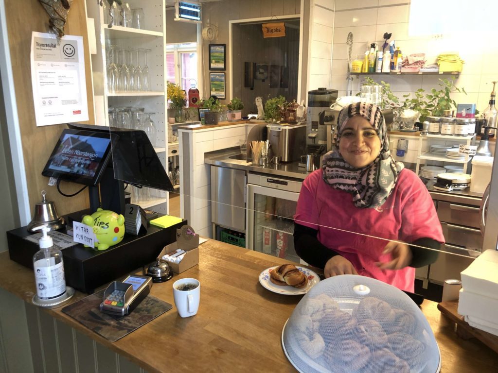 SMILENDE BAKESJEF: Rajaa Aljuhamni er bakeansvarlig på Løten Nærstasjon, men hun trør også til bak kassa når det trengs. FOTO: Marit Amundsen.