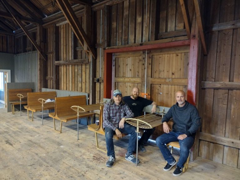 GAMMELT INTERIØR: Godshuset har fått sitteplasser fra gamle togsett i gave av Jernbaneverket. Bjørn Flaaseth, (f.v) og Terje Olsrud prøvesitter 2-seteren mens Sølve Fuglseth har tatt sjefsstolen. Alle tre sitter i styret for Godshuset og har hatt mange timer med dugnad.