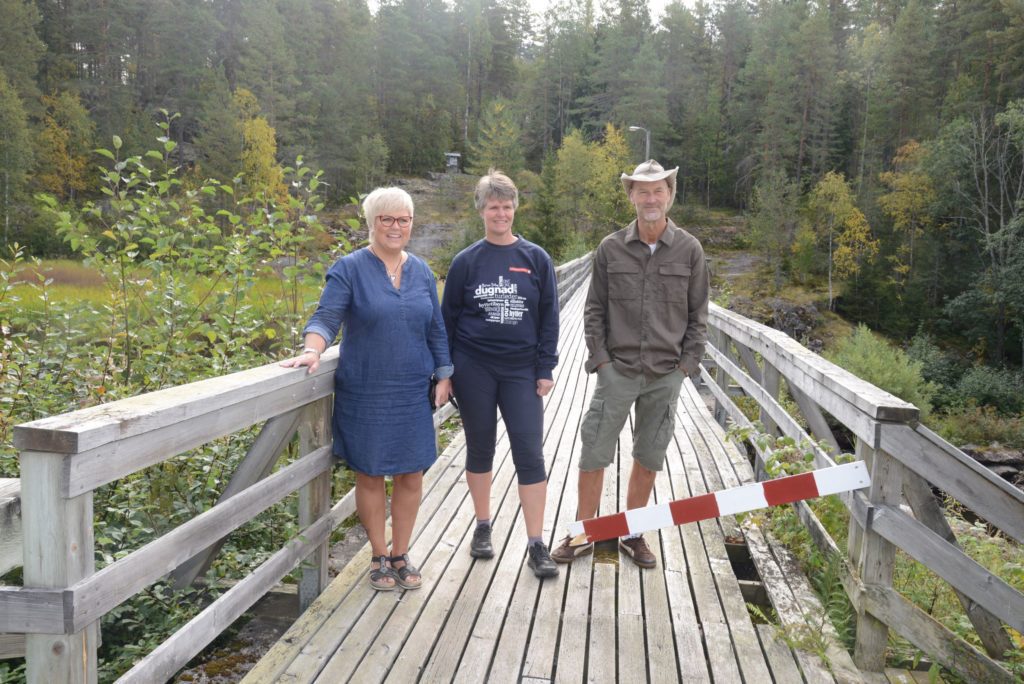 GLAD FOR NY BRU: Bente Hagen (kultursjef Løten kommune), Margrete Ruud Skjeseth (daglig leder Hamar og Hedemarken Turistforening), Jarl Holstad (leder Klevfos industrimuseum) er glad for at det blir mulig å ta seg over Svartelva igjen på stedet. Foto: Hans Kroglund.