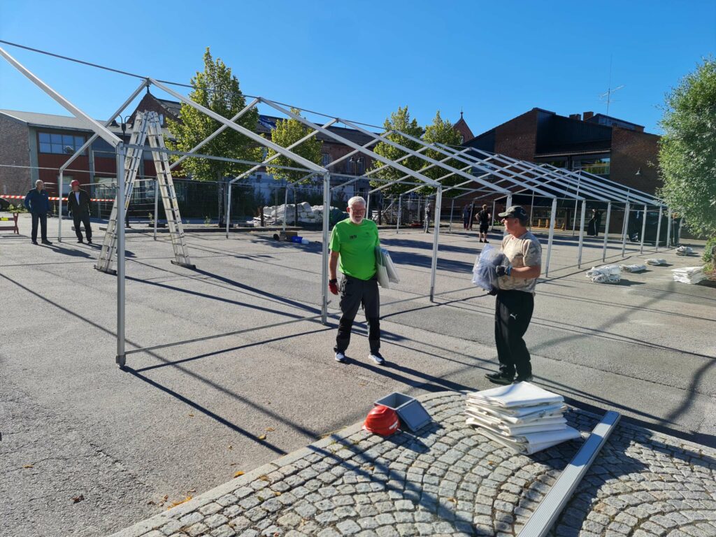 KLARGJØR SENTRUM TIL FEST: I dag og frem mot helga er dugnadsfolk i gang med å rigge til fine dager i sentrum av Løten. Trond Haraldsen er en av de frivillige som stiller til dugnad. Her er han sammen med Terje Haverstad fra Gudbrandsdal arrangementsservice som blant annet leverer teltet som nå settes opp til festlighetene.